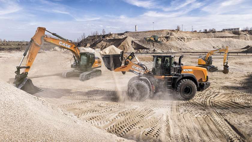 Nowoczesne maszyny na budowach CASE, w tym koparka i ładowarka, pracujące na placu budowy, otoczone piaskiem i kopcami materiałów sypkich.
